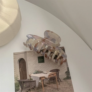 Detail of large acetate hair claw clip with colorful marble texture on a lifestyle background