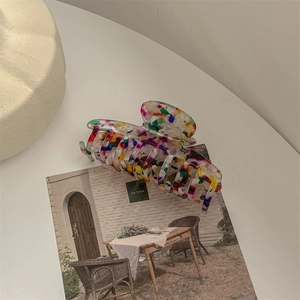 Detail view of large acetate claw clip featuring colorful marbled ink art pattern