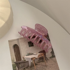 Detail shot of a large pink iridescent acetate hair claw clip with a glossy pearl finish
