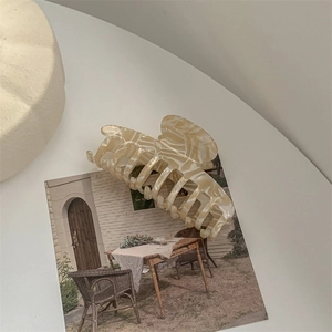 Macro detail of large cream marble acetate hair claw clip with sturdy interlocking teeth