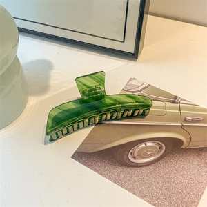 Close-up of a large dark green acetate hair claw clip with elegant marble patterns
