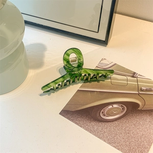 Detailed view of large green acetate hair claw clip with elegant marble texture pattern