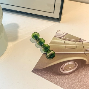 Detailed view of dark green acetate hair claw clip with vertical texture and metal base