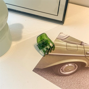Detail shot of the deep green translucent hair claw clip with a glossy acetate finish