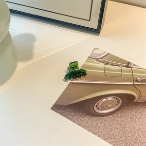 Close-up of a mini transparent green acetate hair claw clip attached to a vintage card