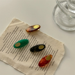 Set of four minimalist amber acrylic hair clips with elegant marble texture on linen fabric