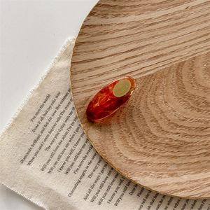 Detailed close-up of amber acrylic hair clip with marble texture on wooden tray