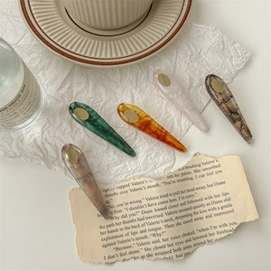 Ensemble élégant de cinq barrettes à cheveux en acétate sur papier blanc froissé