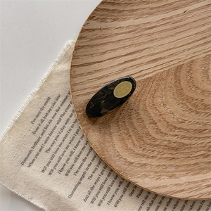Close-up of tortoise shell pattern acrylic hair clip with golden brand logo label