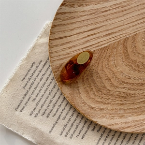 Detail view of tortoiseshell acrylic hair clip with gold label on rustic wooden dish