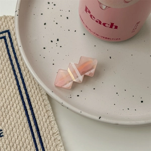 Détail d'une barrette en résine rose à texture marbrée sur une plaque décorative
