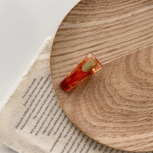 Detail view of amber resin hair clip with gold foil on elegant wooden tray