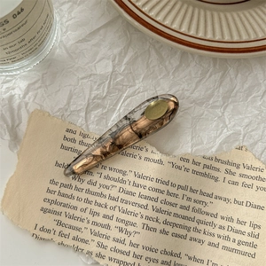 Détail d'une pince à cheveux en résine ambrée marbrée sur fond de papier vintage chic