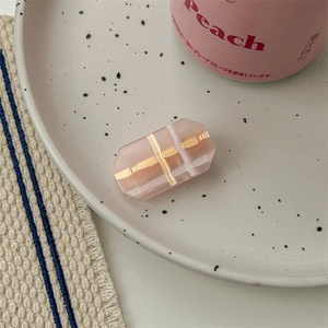 Gros plan d'une pince à cheveux rose quadrillée sur une assiette en porcelaine à pois