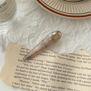 Pince à cheveux en résine ambrée avec logo doré sur papier vintage et fond bougie