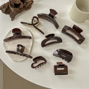 French style dark brown acrylic hair claw set on minimalist white ceramic plate