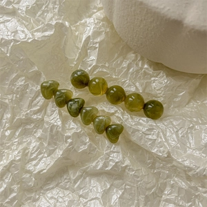 Vue détaillée de deux barrettes vertes avec perles marbrées rondes et en forme de cœur