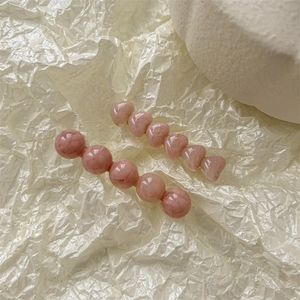 Vue détaillée de barrettes à cheveux en résine de marbre rose sur socle en pierre blanche