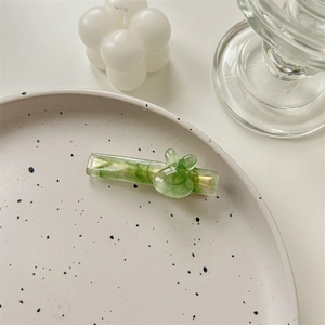 Détail d'une pince à cheveux verte en acétate avec oreilles de lapin et base métal