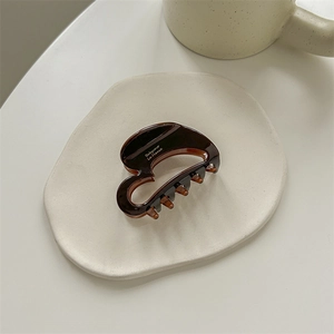 Detailed macro view of chocolate brown tortoiseshell hair claw with white brand lettering