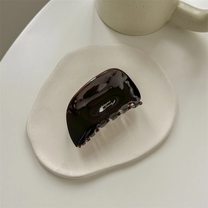 Detail of glossy chocolate brown acrylic hair claw clip with Babyvovo La France logo