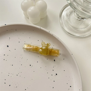 Détail d'une barrette lapin en acétate avec texture marbrée brune sur une assiette blanche
