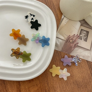 Star-shaped acetate hair clips in various colors displayed on a white plate