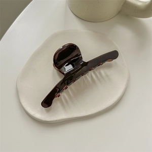 Detail of chocolate brown hair claw featuring golden Handmade in France lettering