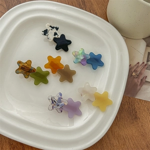 Star-shaped acetate hair clips in multiple marble colors displayed on a ceramic tray