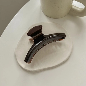 Close-up of chocolate brown acetate hair claw with golden handmade to France text