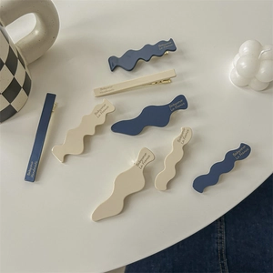 Minimalist blue and cream resin hair clips set with gold lettering on white tabletop