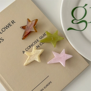 Set of four star-shaped acetate hair clips in marble texture colors on a vintage book