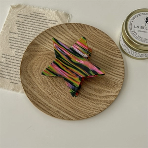 Pince à cheveux en forme d'étoile avec motif marbré coloré sur un plateau en bois