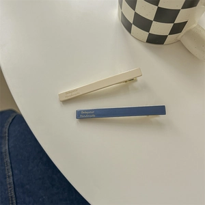 Close-up of minimalist navy and cream hair clips with Babyvovo Handmade print
