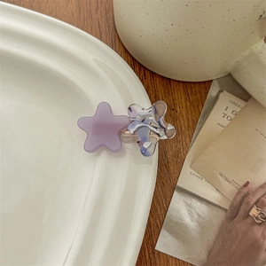 Detailed view of acetate star hair clip in purple marble finish on a white ceramic plate
