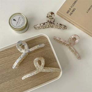 Set of four large acetate hair claws in amber and pearl colors on a wooden tray