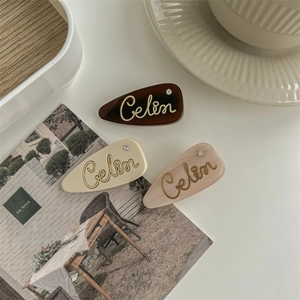 Three minimalist French-style letter hair clips in coffee, cream, and pink colors