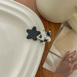 Detail of star-shaped acetate hair clips in black and marble patterns on a ceramic plate