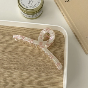 Close-up of a large amber hair claw clip with floral patterns on a wooden tray