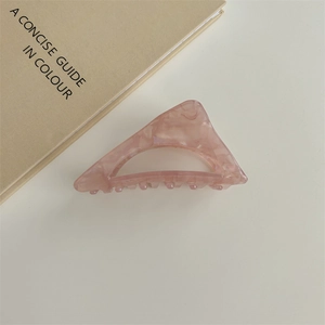 Dettaglio di una pinza per capelli in acetato rosa marmorizzato con design a triangolo