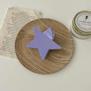 Détail de la pince à cheveux étoile violette en résine sur un plateau en bois rustique