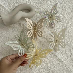 Hollow butterfly hair claws in acetate and cream colors with a minimalist marble texture