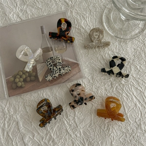 Mini acetate hair claws in various patterns like tortoiseshell and checkered on white fabric