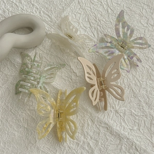 Five elegant acetate butterfly hair claws in beige and marble patterns with gold metal springs