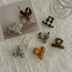 Mini acetate hair claws in various patterns like checkered and marble on white fabric