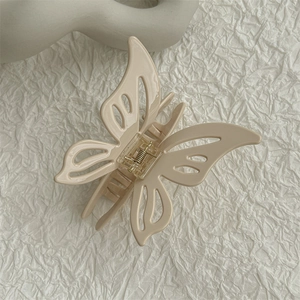 Macro view of cream acetate hollow butterfly hair claw clip with matte finish details
