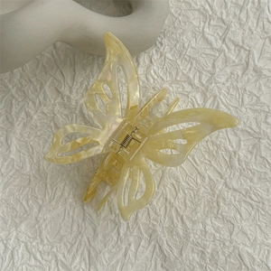 Close-up of hollow butterfly hair claw clip in cream beige acetate with marble texture