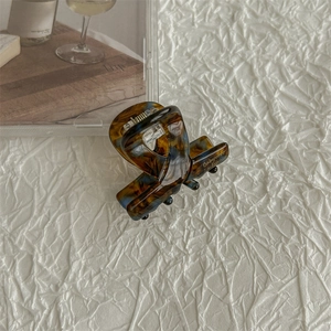 Detail of tortoise shell mini hair claw with gold logo and strong silver metal spring