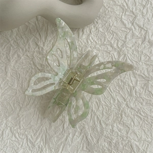 Detailed close-up of hollow butterfly acetate hair claw clip with cream marble texture