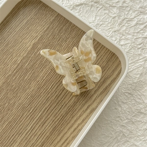 Détail d'une pince à cheveux papillon avec texture écaille crème et marron